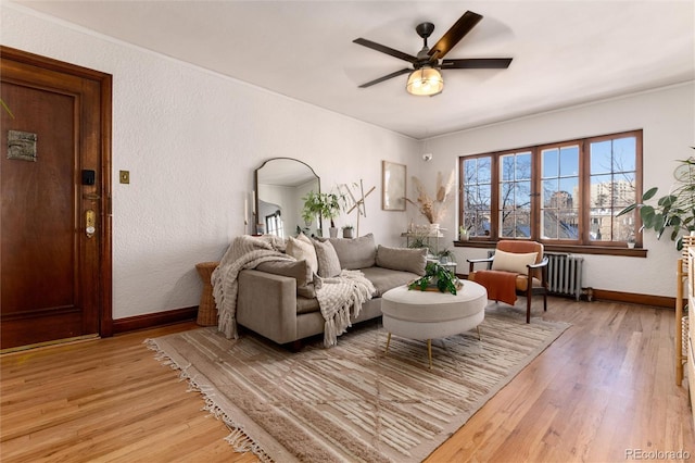 living room with radiator, ceiling fan, and light wood-type flooring