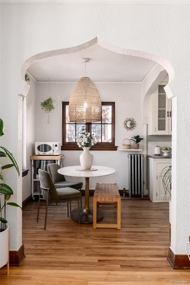 dining room featuring ornamental molding, radiator, and light hardwood / wood-style flooring