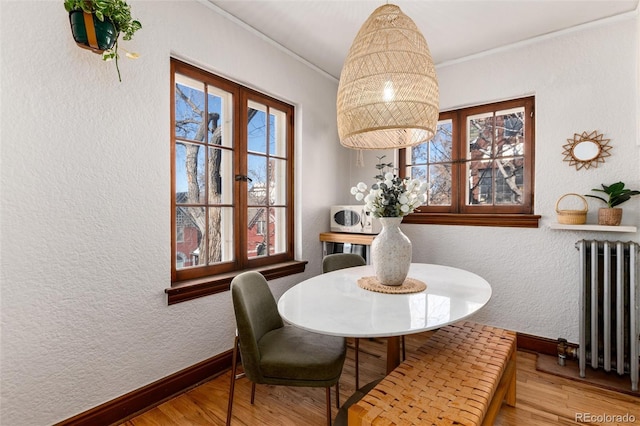 dining space featuring radiator heating unit, ornamental molding, and wood-type flooring