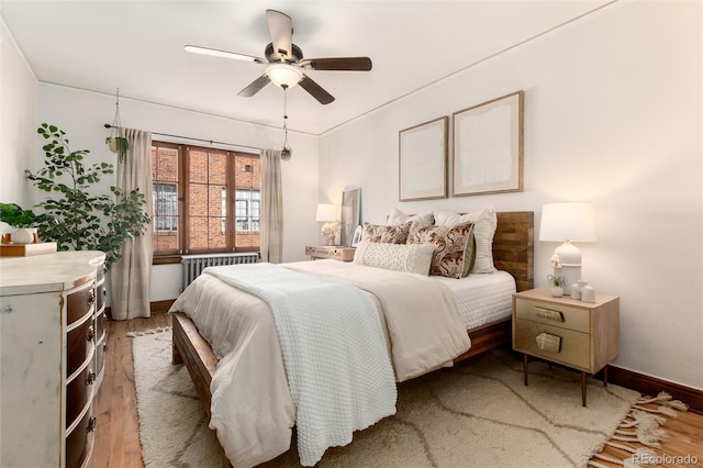 bedroom with radiator heating unit, wood-type flooring, and ceiling fan