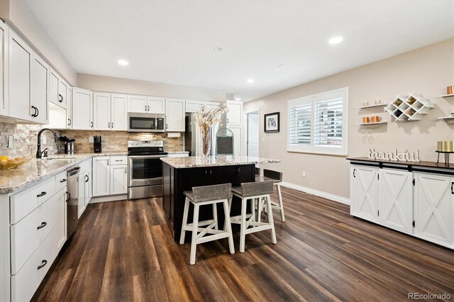 kitchen with white cabinetry, sink, a kitchen breakfast bar, a center island, and stainless steel appliances