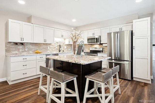 kitchen featuring stainless steel appliances, a kitchen breakfast bar, white cabinets, and a kitchen island