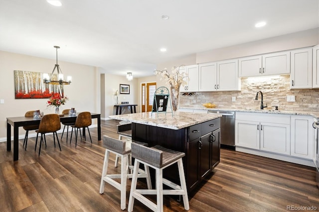 kitchen with white cabinetry, stainless steel dishwasher, decorative light fixtures, and a kitchen island