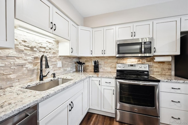 kitchen with stainless steel appliances, sink, white cabinets, and decorative backsplash