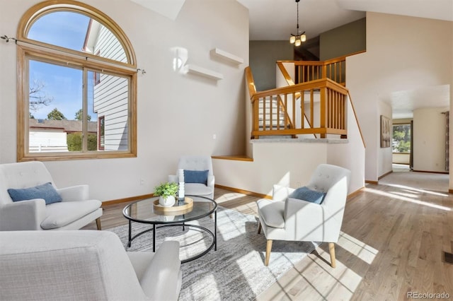 living area with stairway, wood finished floors, visible vents, baseboards, and a high ceiling
