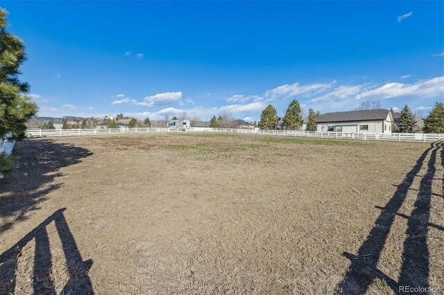 view of yard featuring a rural view, an enclosed area, and fence