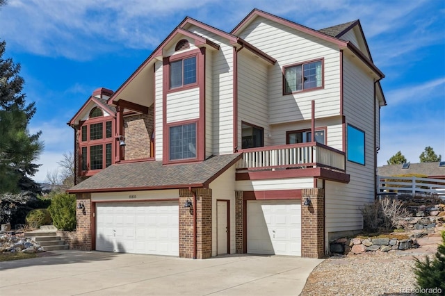 view of front facade with brick siding, concrete driveway, roof with shingles, a balcony, and an attached garage