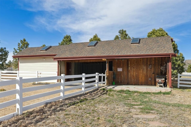 exterior space featuring an exterior structure, a shingled roof, and an outdoor structure