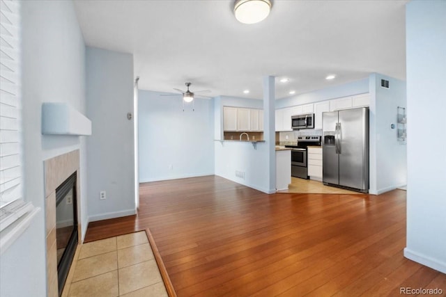 7234 E 38th Ave, Denver, CO 80207 - kitchen featuring stainless steel appliances, light wood finished floors, a ceiling fan, white cabinetry, and open floor plan
