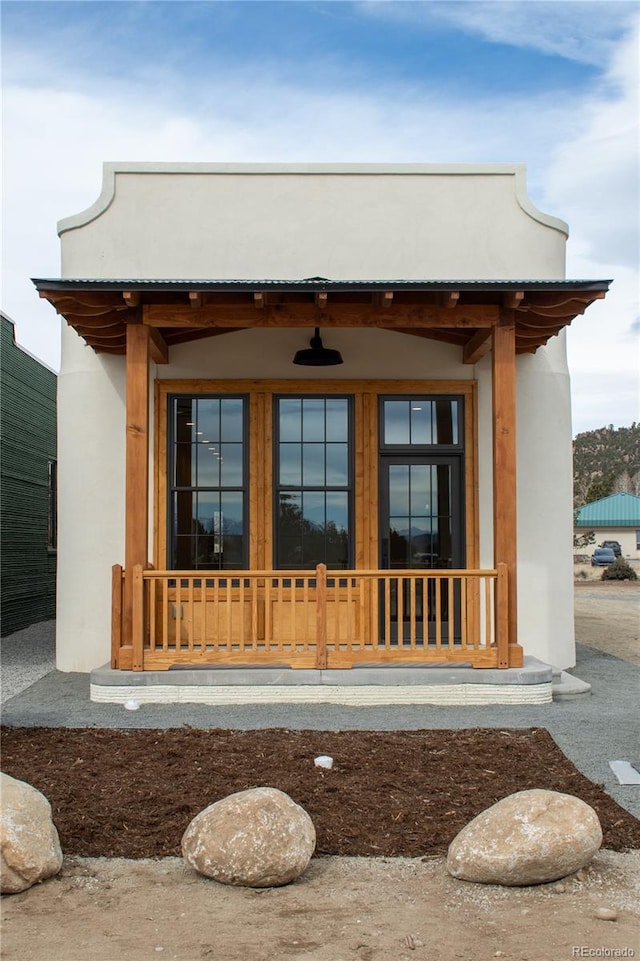 property entrance featuring covered porch and stucco siding