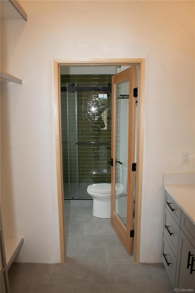 bathroom with tile patterned flooring, a shower stall, vanity, and toilet