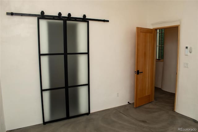 unfurnished room with concrete floors and a barn door