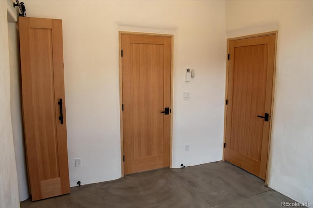 unfurnished bedroom with concrete flooring and a barn door