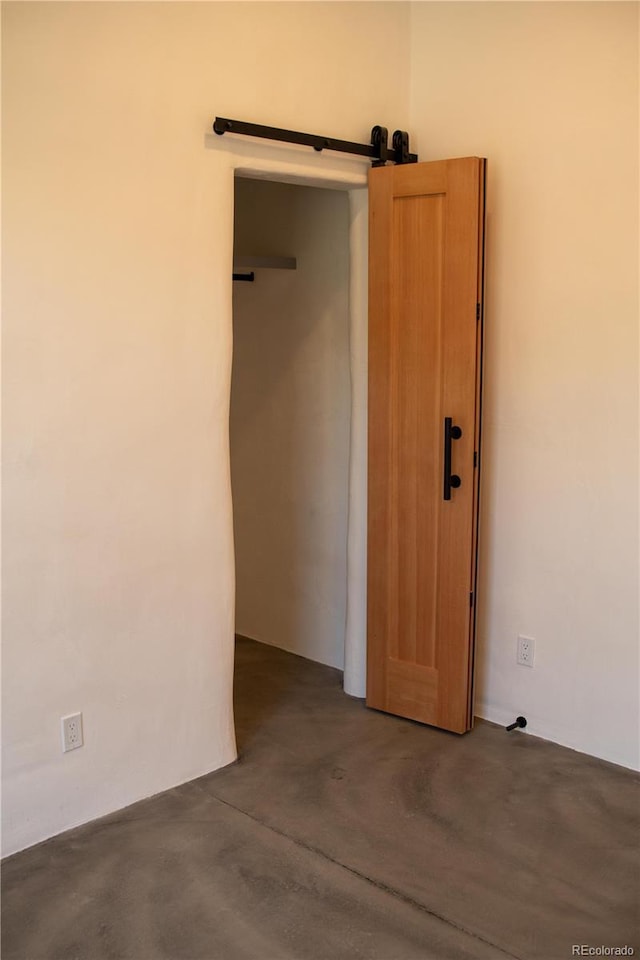 interior space with a barn door and concrete floors