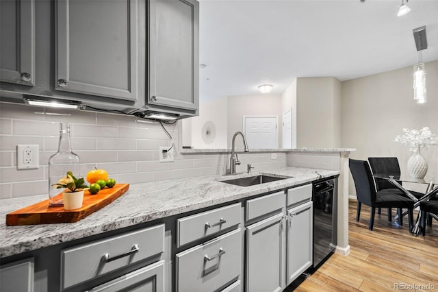 kitchen featuring light stone counters, gray cabinetry, and sink