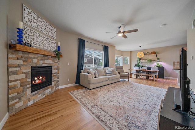 23831 Eagle Bend Ln, Parker, CO 80138 - living room with a ceiling fan, light wood-style flooring, a stone fireplace, and baseboards