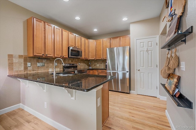 23831 Eagle Bend Ln, Parker, CO 80138 - kitchen featuring stainless steel appliances, light wood-style floors, a peninsula, dark stone counters, and a sink
