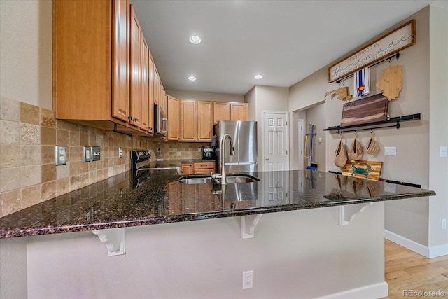 23831 Eagle Bend Ln, Parker, CO 80138 - kitchen featuring stainless steel appliances, a sink, a peninsula, dark stone countertops, and light wood finished floors