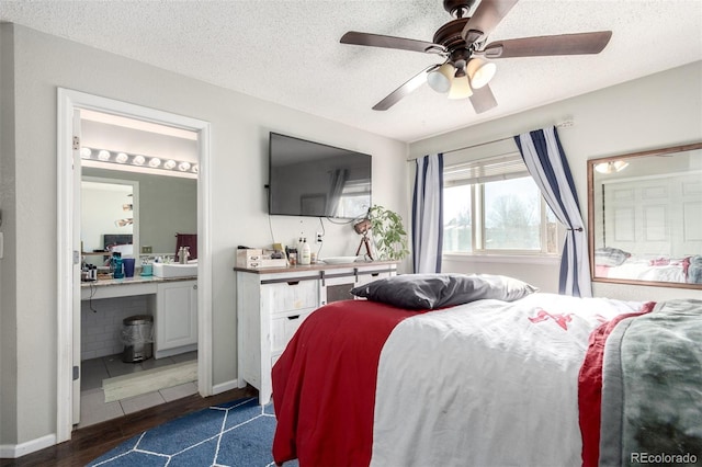 bedroom featuring ensuite bath, ceiling fan, sink, dark hardwood / wood-style floors, and a textured ceiling