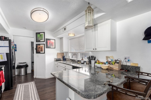 kitchen featuring refrigerator, kitchen peninsula, a textured ceiling, and white cabinetry