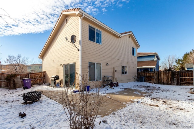 snow covered back of property featuring an outdoor fire pit and cooling unit