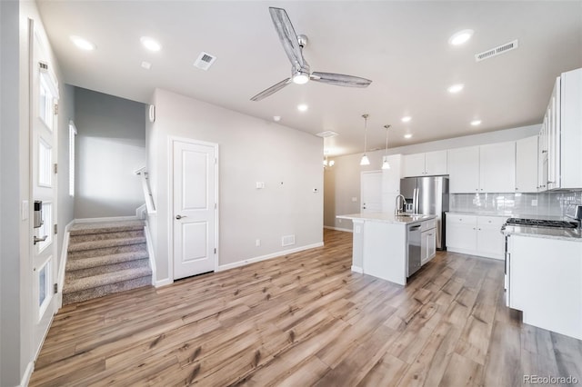 1983 S Poplar Ct, Denver, CO 80224 - kitchen featuring a ceiling fan, light wood finished floors, an island with sink, appliances with stainless steel finishes, and backsplash
