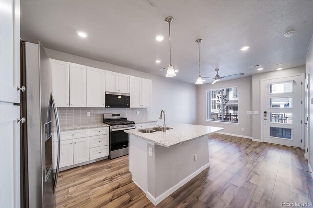 1983 S Poplar Ct, Denver, CO 80224 - kitchen with stainless steel appliances, light wood-style floors, decorative backsplash, white cabinetry, and ceiling fan