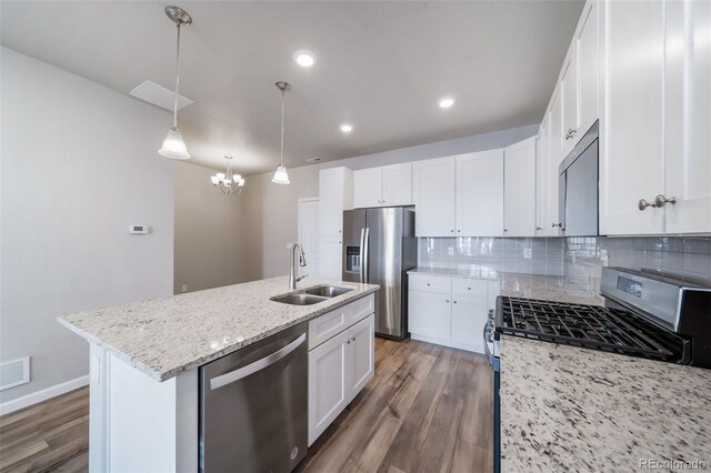 1983 S Poplar Ct, Denver, CO 80224 - kitchen with appliances with stainless steel finishes, wood finished floors, a chandelier, decorative backsplash, and light stone counters