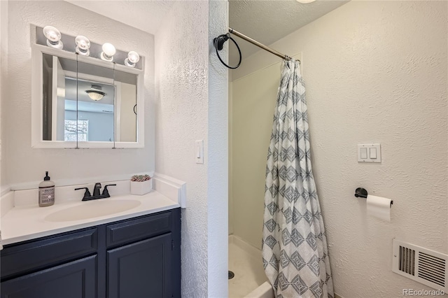 bathroom with a shower with shower curtain, vanity, and a textured ceiling