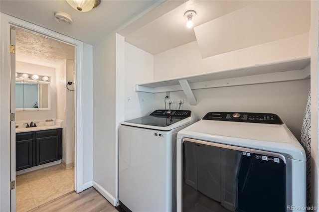 laundry room featuring independent washer and dryer, light hardwood / wood-style flooring, and sink