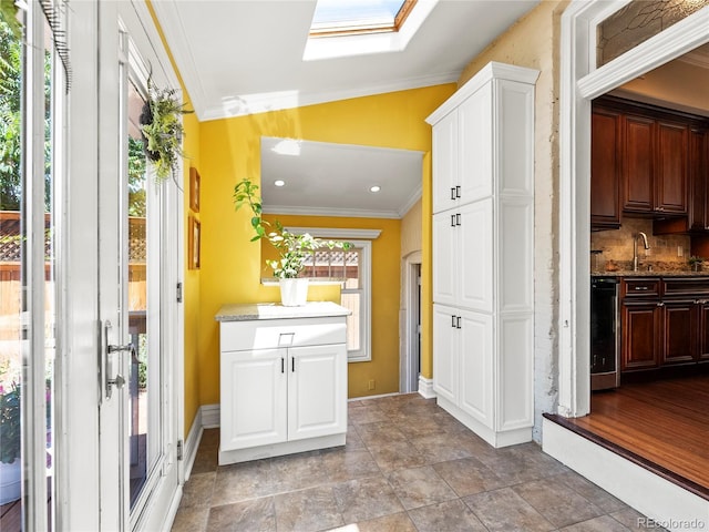 437 S Grant St, Denver, CO 80209 - kitchen with crown molding, a skylight, white cabinetry, backsplash, and dark stone counters