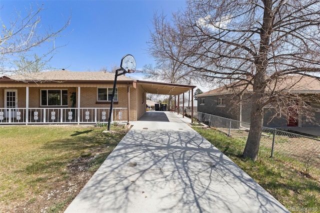 view of front of home featuring concrete driveway, fence, a front lawn, brick siding, and a carport
