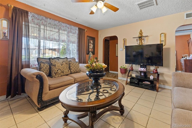 living room featuring visible vents, arched walkways, ceiling fan, and light tile patterned floors
