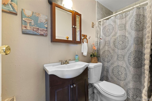 bathroom with a shower with curtain, a textured wall, toilet, and vanity