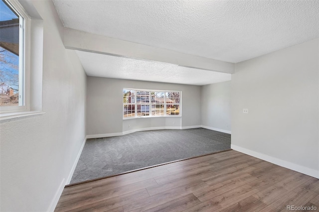 spare room featuring a textured ceiling, baseboards, and wood finished floors