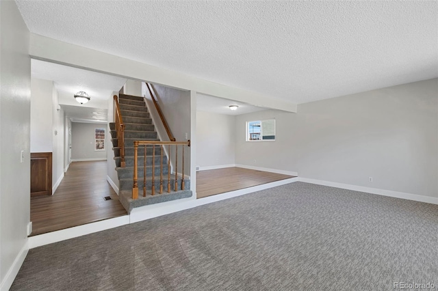 carpeted empty room featuring visible vents, stairs, baseboards, and a textured ceiling