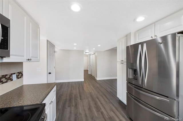 kitchen with stainless steel appliances, dark countertops, backsplash, and white cabinets