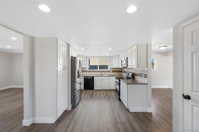 kitchen featuring tasteful backsplash, dark wood finished floors, dark countertops, appliances with stainless steel finishes, and a sink