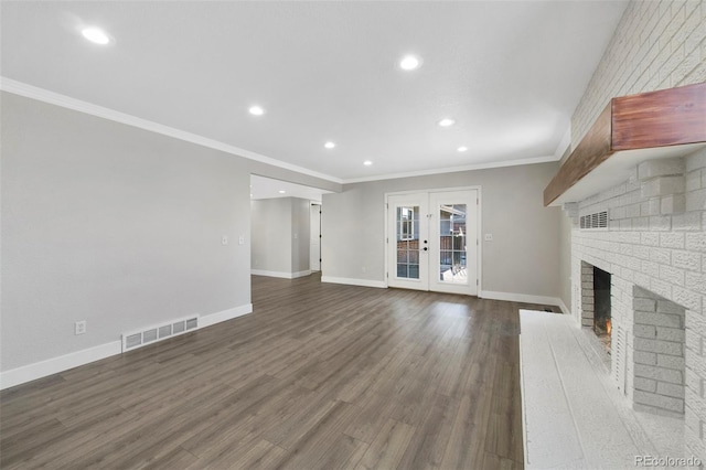 unfurnished living room with wood finished floors, visible vents, baseboards, ornamental molding, and a brick fireplace