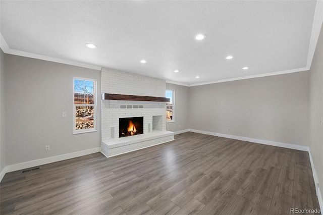 unfurnished living room featuring ornamental molding, a brick fireplace, dark wood-style flooring, and baseboards