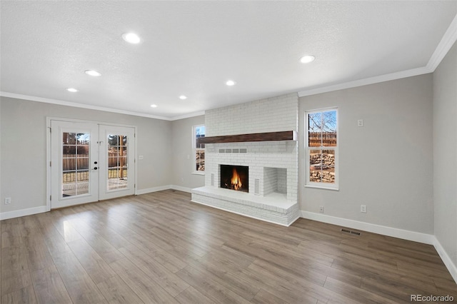 unfurnished living room featuring a textured ceiling, french doors, wood finished floors, and ornamental molding