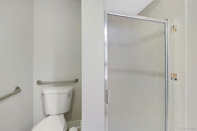 bathroom with toilet and a shower stall