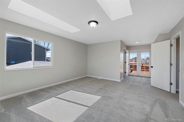 carpeted empty room with a textured ceiling, a healthy amount of sunlight, a skylight, and baseboards