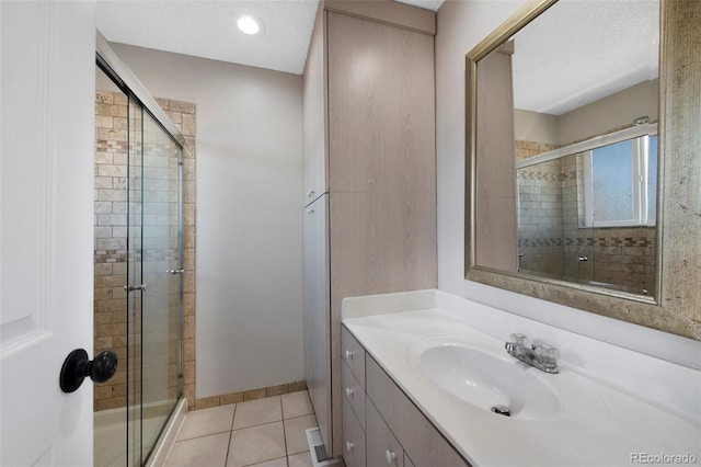 full bathroom with a stall shower, tile patterned flooring, a textured ceiling, and vanity