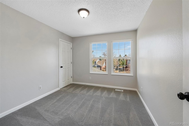 carpeted empty room with visible vents, baseboards, and a textured ceiling