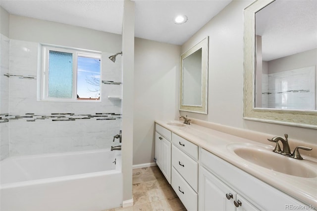 bathroom with double vanity, a sink, bathing tub / shower combination, and baseboards