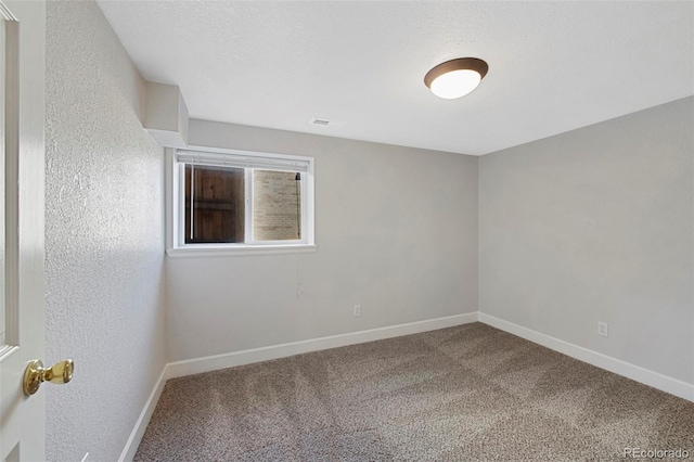 spare room with a textured ceiling, baseboards, and carpet flooring