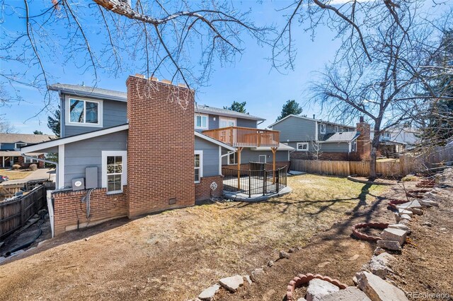 rear view of house featuring brick siding, fence, a chimney, and a lawn