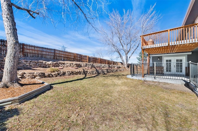 view of yard featuring a deck, french doors, and a fenced backyard