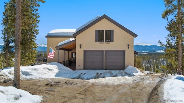 view of front of house featuring stucco siding, a garage, and a mountain view